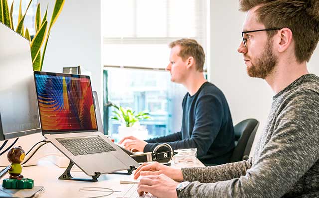 Two Website Designers sit at their workstations in the process of creating responsive mobile websites